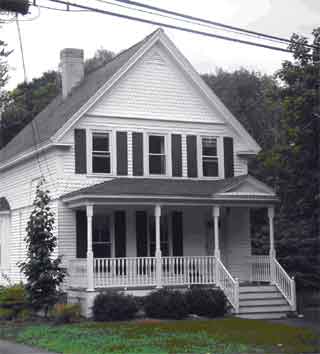 The porch of this front-gabled house has a pediment over the entrance stairs.